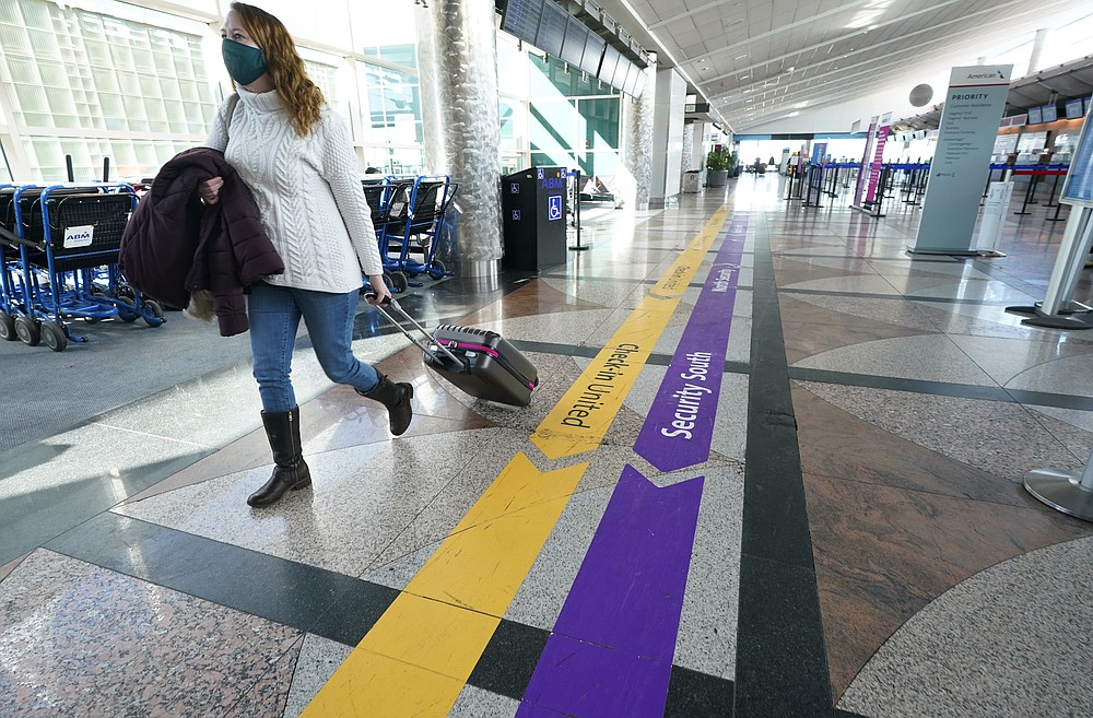 FILE - In this Feb. 18, 2021, file photo, a traveler wears a face covering while hurrying through a near-empty check-in counter area in the main terminal of Denver International Airport in Denver. On Friday, Oct. 15, The Associated Press reported on stories circulating online incorrectly claiming that employees refused to show up to work at five of the airport’s restaurants because of a supposed COVID-19 vaccine mandate. (AP Photo/David Zalubowski, File)