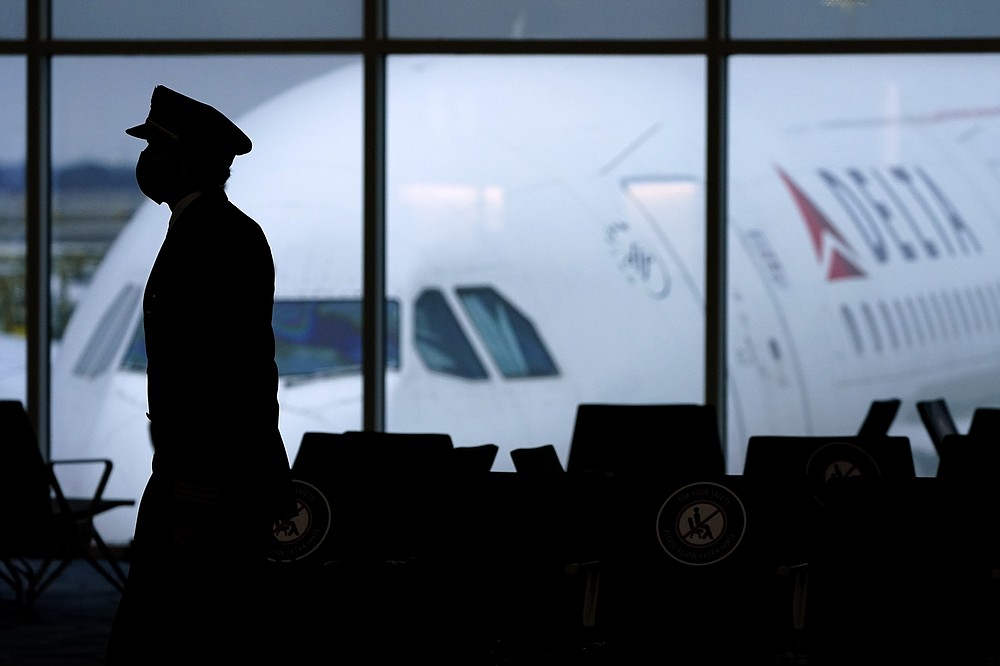 FILE - In this Thursday, Feb. 18, 2021, file photo, a Delta Airlines pilot wears a face mask as he walks through a terminal at Hartsfield-Jackson International Airport in Atlanta. On Friday, Oct. 15, The Associated Press reported on stories circulating online incorrectly claiming a Delta Airlines pilot who had recently been vaccinated for COVID-19 died mid-flight within the last 10 days, forcing the plane to make an emergency landing. (AP Photo/Charlie Riedel, File)