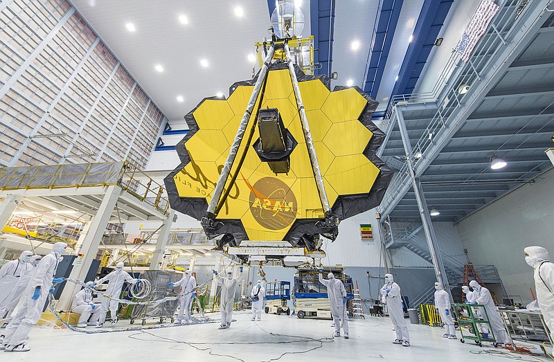 In this 2017 photo made available by NASA, technicians lift the mirror assembly of the James Webb Space Telescope using a crane inside a clean room at NASA's Goddard Space Flight Center in Greenbelt, Md. On Thursday, July 16, 2020, officials announced that the telescope is now scheduled to launch on Oct. 31, 2021. The previous target date was March 2021. (Desiree Stover/NASA via AP)