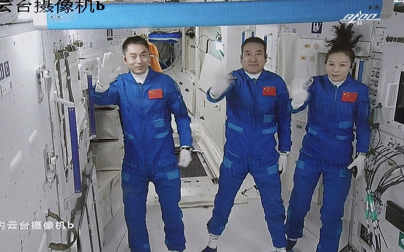 In this photo released by Xinhua News Agency, screen image captured at Beijing Aerospace Control Center in Beijing, China, Saturday, Oct. 16, 2021 shows three Chinese astronauts, from left, Ye Guangfu, Zhai Zhigang and Wang Yaping waving after entering the space station core module Tianhe. China's Shenzhou-13 spacecraft carrying three Chinese astronauts on Saturday docked at its space station, kicking off a record-setting six-month stay as the country moves toward completing the new orbiting outpost. Chinese characters,  left, read &quot;Platform Camera B.&quot; (Tian Dingyu/Xinhua via AP)