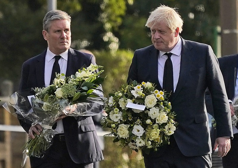 British Prime Minister Boris Johnson, right, and Leader of the Labour Party Keir Starmer carry flowers as they arrive at the scene where a member of Parliament was stabbed Friday, in Leigh-on-Sea, Essex, England, Saturday, Oct. 16, 2021. David Amess, a long-serving member of Parliament was stabbed to death during a meeting with constituents at a church in Leigh-on-Sea on Friday, in what police said was a terrorist incident. A 25-year-old man was arrested in connection with the attack, which united Britain's fractious politicians in shock and sorrow. (AP Photo/Alberto Pezzali)