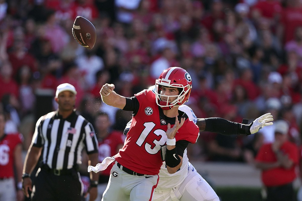 Georgia quarterback Stetson Bennett (13) fumbles the ball as Kentucky defensive end Josh Paschal (4) hits him during the first half of an NCAA college football game Saturday, Oct. 16, 2021 in Athens, Ga. (AP Photo/Butch Dill)