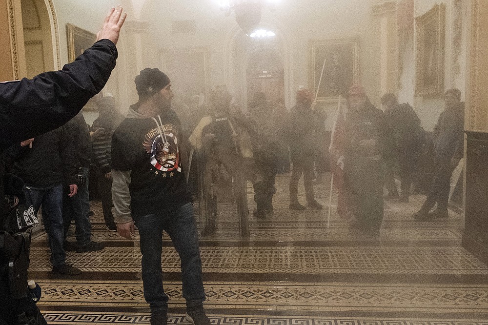FILE - In this Jan. 6, 2021, file photo, smoke fills the walkway outside the Senate Chamber as supporters of President Donald Trump, including Eric Bochene, far right, are confronted by U.S. Capitol Police officers inside the Capitol in Washington. Bochene is one of at least five people charged in the riot at the U.S. Capitol on Jan. 6 who have chosen to defend themselves in court, brushing aside federal judges’ repeated warnings about the risks of trying to navigate their high-stakes cases without an attorney. (AP Photo/Manuel Balce Ceneta, File)