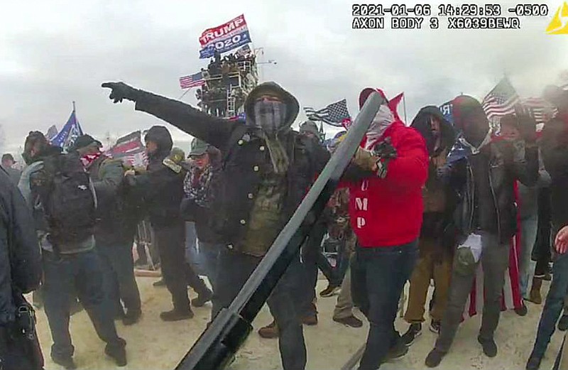 This image, from the criminal complaint, shows a Brian Christopher Mock, center, in an image captured in police body worn video on the West Front of the U.S. Capitol in Washington, on Jan. 6, 2021. Mock is one of at least five people charged in the riot at the U.S. Capitol on Jan. 6 who have chosen to defend themselves in court, brushing aside federal judges' repeated warnings about the risks of trying to navigate their high-stakes cases without an attorney. (Justice Department via AP)