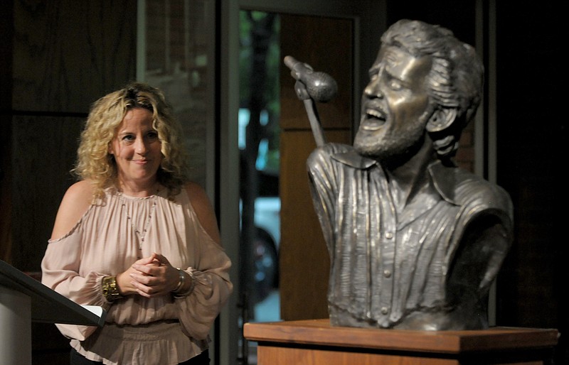 Amy Helm, daughter of musician Levon Helm, looks at a bronze bust of her late father after it was unveiled in 2018. The bust was placed near Helm’s boyhood home. The house was moved from Turkey Scratch to downtown Marvell, where Amy Helm will perform at the Levon Helm Downhome Jubilee on Saturday. (NWA Democrat-Gazette file photo)