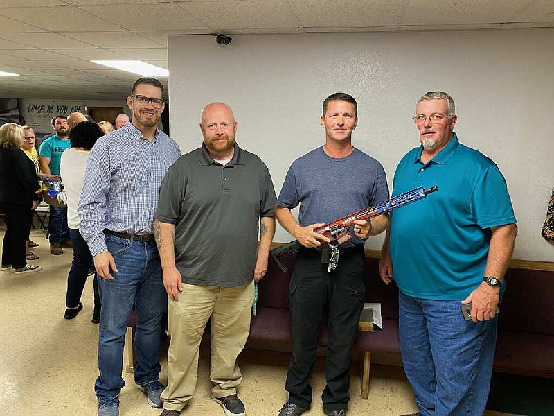 PHOTO BY BRYAN HALL  Shan Cobb (left), John Bartholomew, Bobby Thiel, and Bryan Hall at Splitlog Baptist Church banquet. Seneca officer Bobby Thiel wins rifle at event.