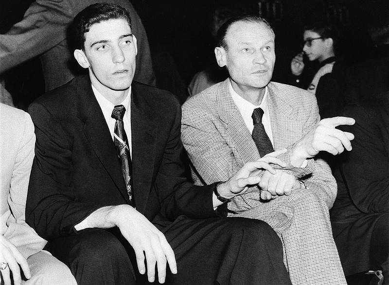 FILE - In this February 1953, file photo, Clarence "Bevo" Francis, left, reaches over to tug the sleeve of New York Knicks coach Joe Lapchick as they watch a basketball game between the Knicks and the Ft. Wayne Pistons at New York's 69th Regiment Armory in New York. Lapchick was the first coach of the New York Knicks. Joe Lapchick's initial efforts to integrate what would become the NBA was thwarted in 1947 but he signed Nat “Sweetwater” Clifton in 1950. (AP Photo/File)