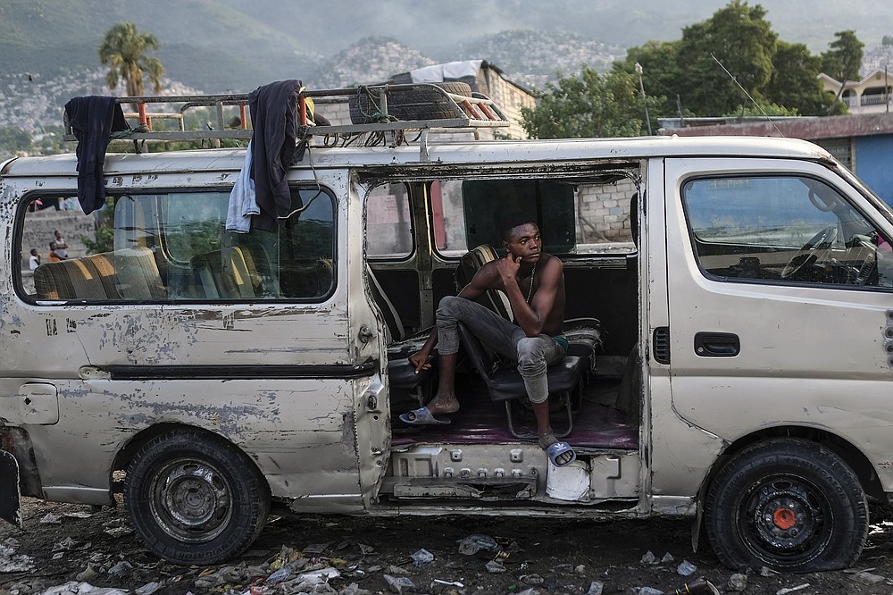 A man rests in an abandoned truck during the general strike in Port-au-Prince, Haiti, Monday, Oct. 18, 2021. Workers angry about the nation's lack of security went on strike in protest two days after 17 members of a US-based missionary group were abducted by a violent gang. (AP Photo/Matias Delacroix)