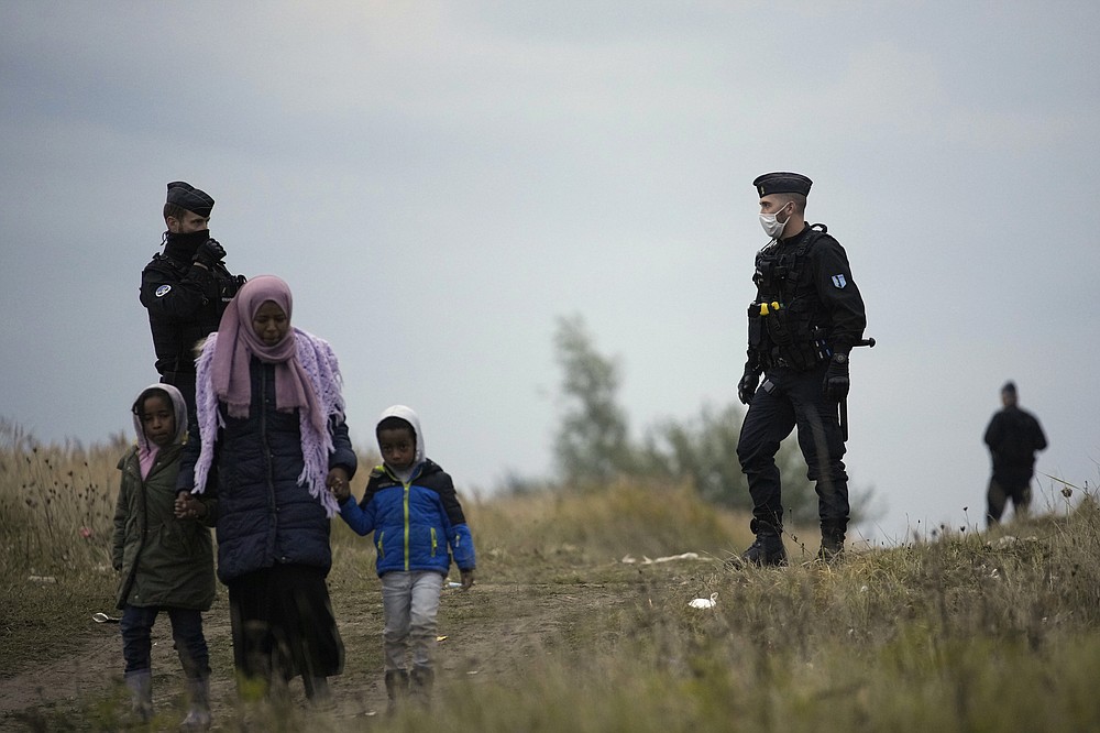 Police officers patrol near a migrant camp in Calais, northern France, Thursday, Oct. 14, 2021. While some migrants with money can pay to go to Britain on flimsy, overcrowded boats in often dangerous waters, the ones who can’t have to jump on one of the tens of thousands commercial trucks that pass each week between France and Britain. (AP Photo/Christophe Ena)