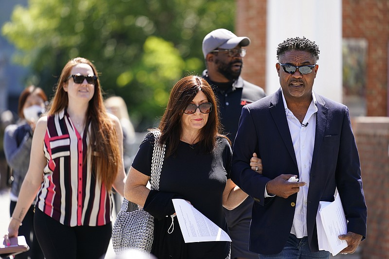 FILE - In this May 14, 2021, file photo, former NFL players Ken Jenkins, right, and Clarence Vaughn III, center right, along with their wives, Amy Lewis, center, and Brooke Vaughn, left, carry petitions demanding equal treatment for everyone involved in the settlement of concussion claims against the NFL, to the federal courthouse in Philadelphia, in this Friday, May 14, 2021, file photo.  Lawyers for the NFL and retired players filed proposed changes to the $1 billion concussion settlement on Wednesday, Oct. 20, 2021, to remove race-norming in dementia testing, which made it more difficult for Black players to qualify for payments. (AP Photo/Matt Rourke, File)