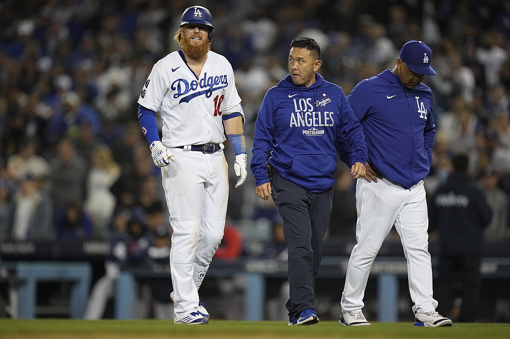 Los Angeles Dodgers' Justin Turner is escorted off the field after grounding out during gate seventh inning against the Atlanta Braves in Game 4 of baseball's National League Championship Series Wednesday, Oct. 20, 2021, in Los Angeles. (AP Photo/Jae Hong)