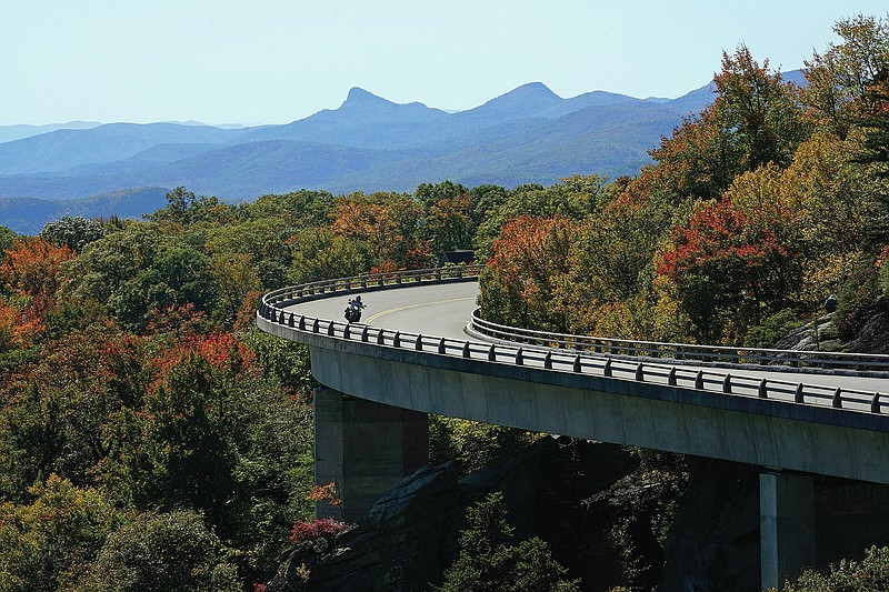 A motorcyclist navigates the Linn Cove Viaduct at Grandfather Mountain along the Blue Ridge Parkway near Linville, N.C., Monday, Oct. 18, 2021, as autumn colors begin to appear at certain elevations. (AP Photo/Gerry Broome)