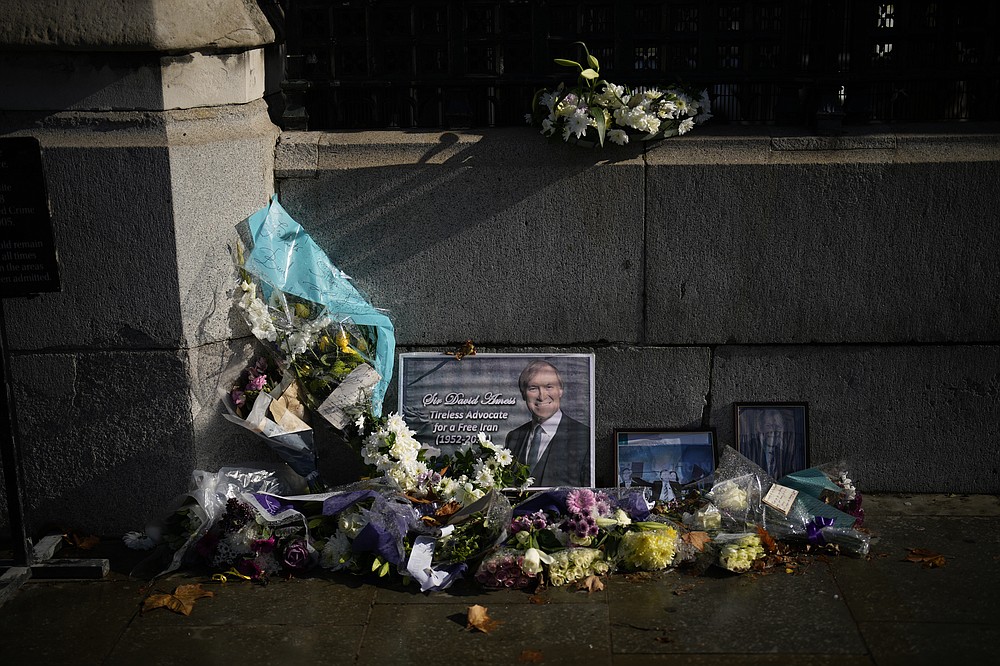 Floral tributes and pictures of British Member of Parliament David Amess lie placed outside the Houses of Parliament in London, Wednesday, Oct. 20, 2021. British lawmaker David Amess was killed on Friday during a meeting with constituents at the Belfairs Methodist church, in Leigh-on-Sea, Essex, England. (AP Photo/Matt Dunham)
