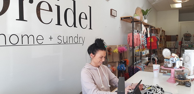 Jacey Griggs runs the front desk and greets customers on a Thursday afternoon at Dreidel Home + Sundry. The shop features curios and knickknacks. Owner Kaydee Waren says that it is the local emphasis that is key to her success. (Staff photo by Junius Stone.)