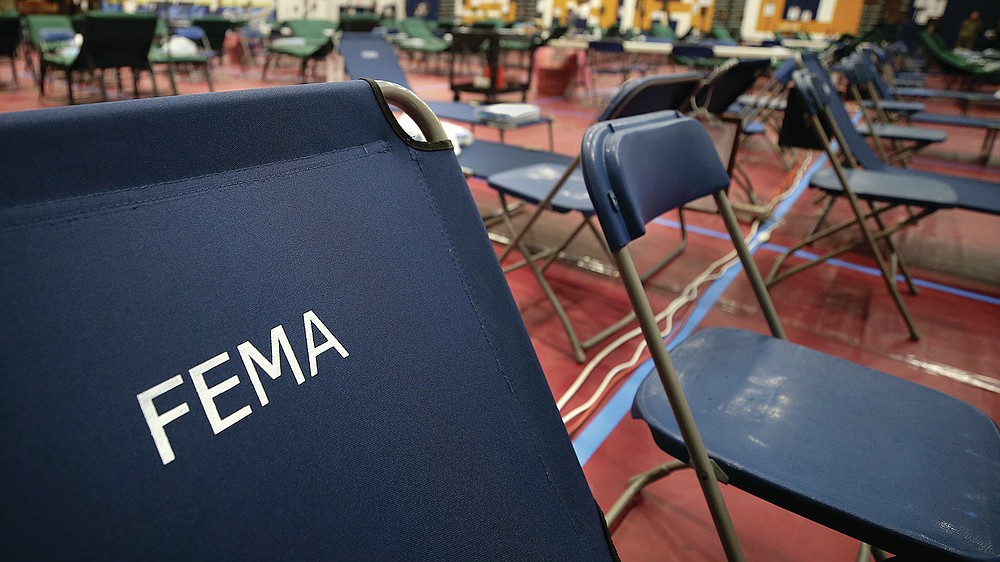 FILE - In this March 24, 2020, file photo, a portable cot with the Federal Emergency Management Agency logo FEMA printed on the backrest, along with other cots, line the basketball court at a makeshift medical facility in a gymnasium at Southern New Hampshire University in Manchester, N.H. On Friday, Oct. 22, The Associated Press reported on stories circulating online incorrectly claiming FEMA workers aren’t subject to a vaccine mandate, and also falsely asserting that they’re being used to replace health care personnel who refuse to comply with such mandates. (AP Photo/Charles Krupa, File)