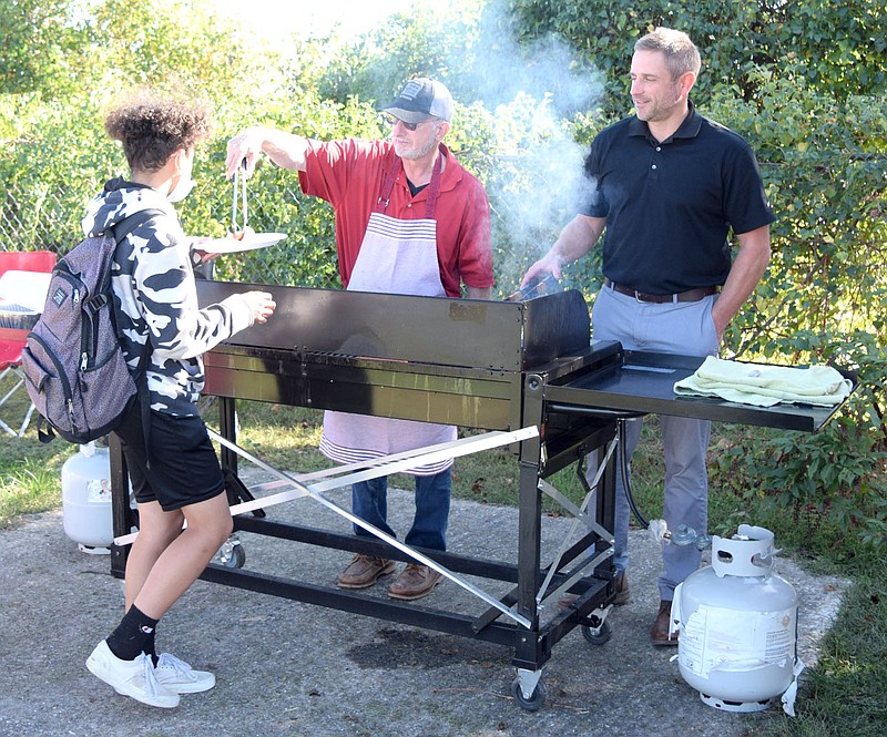 Westside Eagle Observer/MIKE ECKELS
Ricky Thor (left) gets a hot dog from Mike Morse while coworker Ken Jennings watches fresh hot dogs roasting on the grill during the Farm Bureau Insurance Bulldog luncheon at Bulldog Stadium in Decatur Friday afternoon. Farm Bureau is a big supporter of not only athletics in Decatur but also FFA and other club based activities.