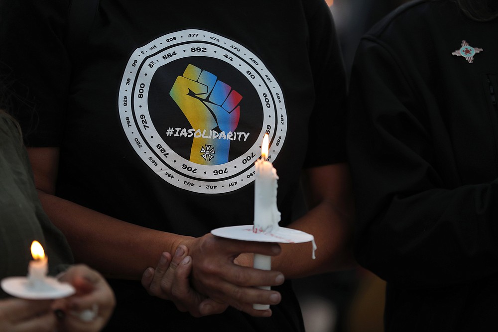 Movie industry worker Hailey Josselyn, wearing a t-shirt of the International Alliance of Theatrical Stage Employees (IATSA), holds a candle during a vigil to honor cinematographer Halyna Hutchins in Albuquerque, N.M., Saturday, Oct. 23, 2021. Hutchins was killed when actor Alec Baldwin fired a weapon on a film set that a crew member told him was safe. The tragedy has led to calls for fundamental change in Hollywood: the banning of real guns on sets. (AP Photo/Andres Leighton, file)