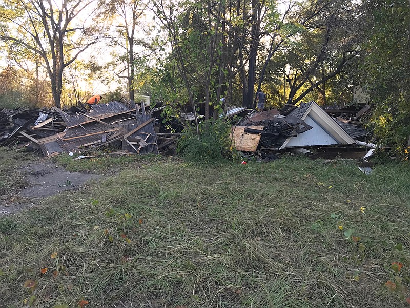 Local residents sift through the burned wreckage of a vintage wood-frame home in the 700 block of Pecan Street Sunday evening. The house caught fire Sunday morning and the Texarkana Fire Department said the city has a suspect in  custody. (Staff Photo By Greg Bischof)