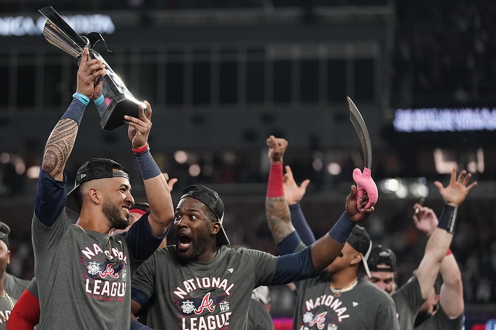 Atlanta Braves' Eddie Rosario holds the MVP trophy as he celebrates with Guillermo Heredia after winning Game 6 of baseball's National League Championship Series against the Los Angeles Dodgers Sunday, Oct. 24, 2021, in Atlanta. The Braves defeated the Dodgers 4-2 to win the series. (AP Photo/Ashley Landis)