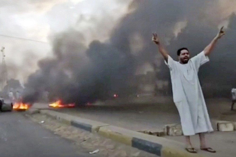 In this frame taken from video a man shouts slogans during a protest in Khartoum, Sudan, Monday, Oct. 25, 2021. Military forces arrested Sudan's acting prime minister and senior government officials Monday, disrupted internet access and blocked bridges in the capital Khartoum, the country's information ministry said, describing the actions as a coup. In response, thousands flooded the streets of Khartoum and its twin city of Omdurman to protest the apparent military takeover. Footage shared online appeared to show protesters blocking streets and setting fire to tires as security forces used tear gas to disperse them. (New Sudan NNS via AP)