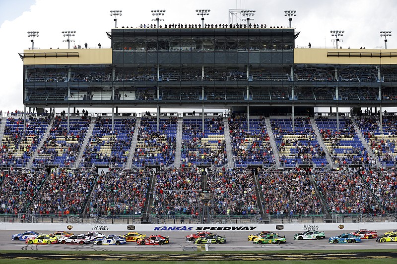Fans watch from the grandstand as race cars cross the start/finish line at the start of a NASCAR Cup Series auto race at Kansas Speedway in Kansas City, Kan., Sunday, Oct. 24, 2021. (AP Photo/Colin E. Braley)