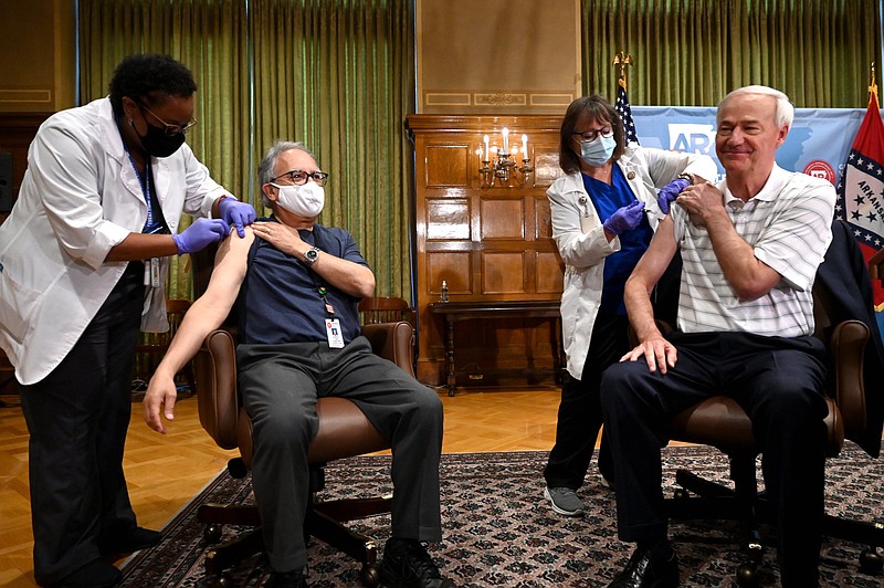 From left, Ebony Crutchfield, RN, gives Dr. Jose Romero, Secretary of the Department of Health, his flu vaccine as Neldia Dycus, RN, Regional Director at the Arkansas Department of Health, gives Governor Hutchinson his vaccine before the start of the Governor's weekly address on Arkansas' response to COVID-19 on Tuesday, Oct. 26. (Arkansas Democrat-Gazette/Stephen Swofford)