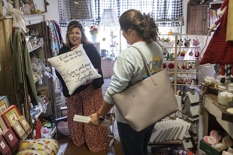 Ginger Pigg suggests a gift to a customer in her gift boutique The Perfect Pigg in Cumming, Ga. on Thursday afternoon, Oct. 22, 2021. She says she is struggling to get products to her store in a timely way. (AP Photo/Ben Gray)