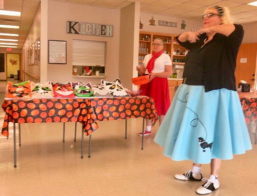 Westside Eagle Observer/SUSAN HOLLAND
Melissa Provence (right), director of the Billy V. Hall Senior Activity Center, acts out one of the words on the Halloween bingo card during a bingo session at the Center Tuesday morning, Oct. 26. Her assistant, Cheryl Waeltz, waits in the background to show Provence the next word to be announced during the morning's festivities.