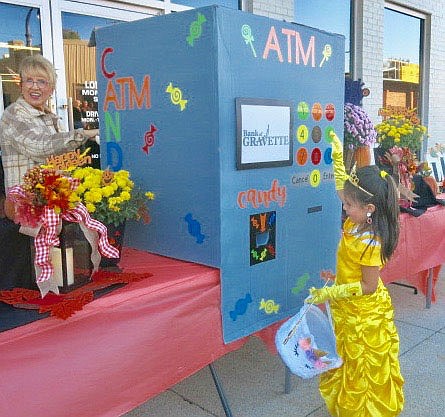 Westside Eagle Observer/SUSAN HOLLAND
A young princess pushes the buttons on the giant ATM machine at Bank of Gravette as Debbie Strickland (left) works behind the scenes to make sure each child who visits the machine gets a piece of candy. Youngsters enjoy visiting the ATM as much as Mom and Dad do!