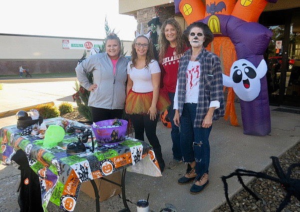 Westside Eagle Observer/SUSAN HOLLAND
Ladies from the Grand Savings Bank pose for a photo as they pause from handing out candy to trick or treaters. A giant spider left his web and joined them as they greeted youngsters at the east entrance to the bank.