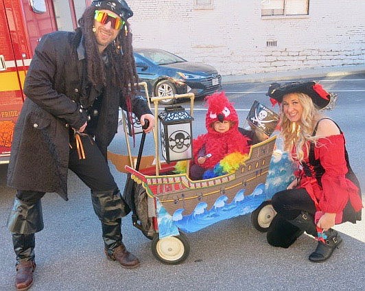 Westside Eagle Observer/SUSAN HOLLAND
Steven and Amy Woolsey, of Rogers, dressed as pirates, pose with their daughter Willow, dressed as a parrot. Willow's wagon was decorated to resemble a pirate ship and the family attracted several admiring glances as they enjoyed Trick or Treat on Main Street.