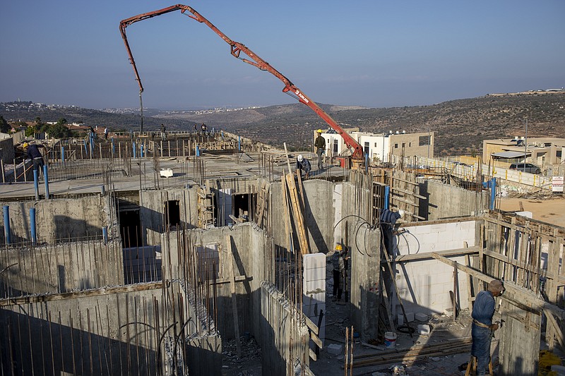 FILE - In this Monday, Oct. 25, 2021 file photo, Palestinian laborers work building new houses in the West Bank Jewish settlement of Bruchin near the Palestinian town of Nablus, Monday, Oct. 25, 2021. An Israeli settlement monitor said Wednesday that Israel has approved about 3,000 settler homes in the occupied West Bank. The decision by a government committee came a day after the Biden administration issued its strongest condemnation yet of the proposed construction. (AP Photo/Ariel Schalit, File)