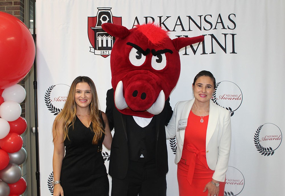 Sisters Daniela Jankovska (left) and Young Alumni Award winner Olivera Jankovska are joined by Big Red for a photo at the UA Alumni Association awards ceremony. (NWA Democrat-Gazette / Carin Schoppmeyer)