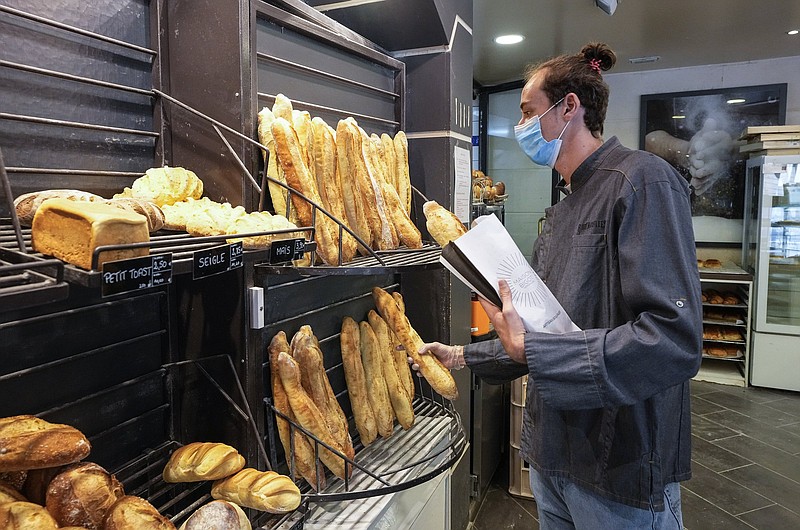 Baker Hugo Hardy prepares baguettes to be sold at Bigot bakery in Versailles, west of Paris, Tuesday, Oct. 26, 2021. A worldwide increase in wheat prices after bad harvests in Russia is forcing French bakers to raise the price of that staple of life in France the baguette. Boulangeries around France have begun putting up signs warning their customers of an increase in the price of their favorite bread due to rising costs. (AP Photo/Michel Euler