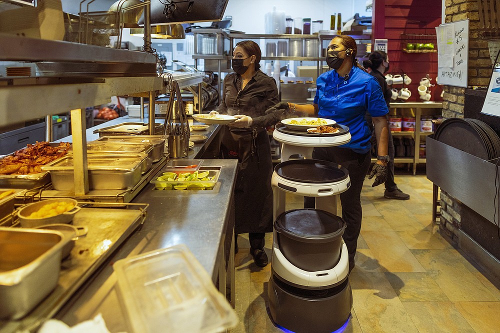 A Servi robot is loaded to take customers their food at Sergio’s Restaurant in Miami. Staffing shortages are causing problems in the restaurant industry nationwide and the problem has owners willing to try robots to fill the gaps. (The New York Times/Saul Martinez)