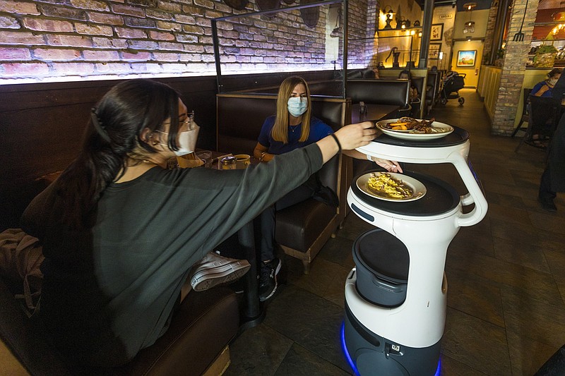 A Servi robot takes customers their food at Sergio’s Restaurant in Miami. Servi uses cameras and laser sensors to carry plates of food from the kitchen to customers’ tables in the dining room. (The New York Times/Saul Martinez)