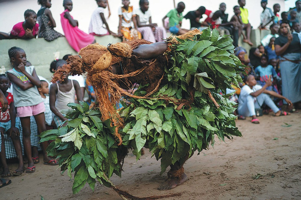 A man dressed as the Kankurang dances during a Mandinka ritual in Bakau, Gambia, Saturday, Oct. 2, 2021. The Kankurang rite was recognized in 2005 by UNESCO, which proclaimed it a cultural heritage. Despite his fearsome appearance, the Kankurang symbolizes the spirit that provides order and justice and is considered a protector against evil. He appears at ceremonies where circumcised boys are taught cultural practices, including discipline and respect. (AP Photo/Leo Correa)