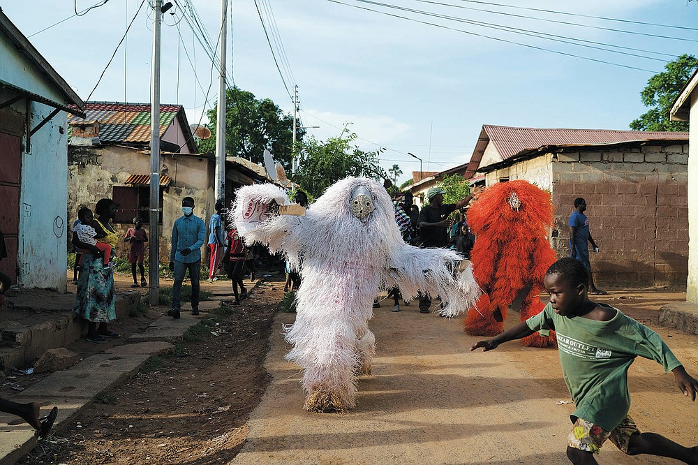 A boy runs away from men dressed as Kankurang during a ritual procession in Bakau, Gambia, Saturday, Oct. 2, 2021. The Kankurang rite was recognized in 2005 by UNESCO, which proclaimed it a cultural heritage. Despite his fearsome appearance, the Kankurang symbolizes the spirit that provides order and justice and is considered a protector against evil. He appears at ceremonies where circumcised boys are taught cultural practices, including discipline and respect. (AP Photo/Leo Correa)