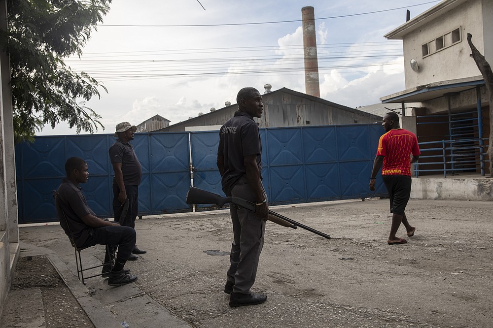 Armed private security guards stand watch at the main entrance of the Shodecosa industrial park, in Port-au-Prince, Haiti, Tuesday, Sept. 28, 2021. Shodecosa is Haiti's largest industrial park, which warehouses most of the 93 percent of the nation's food that is imported. (AP Photo/Rodrigo Abd)