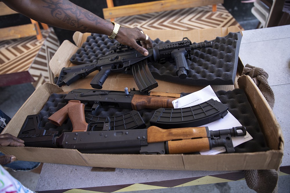 A G9 gang coalition member unpacks weapons that include American-made AK rifles with ammunition, in Port-au-Prince, Haiti, Wednesday, Oct. 6, 2021. While some gangs have turned to kidnapping, like those who captured 17 missionaries and their relatives, the G9 coalition has taken control of the port district, gaining a stranglehold on the country&#x2019;s economy. (AP Photo/Rodrigo Abd)