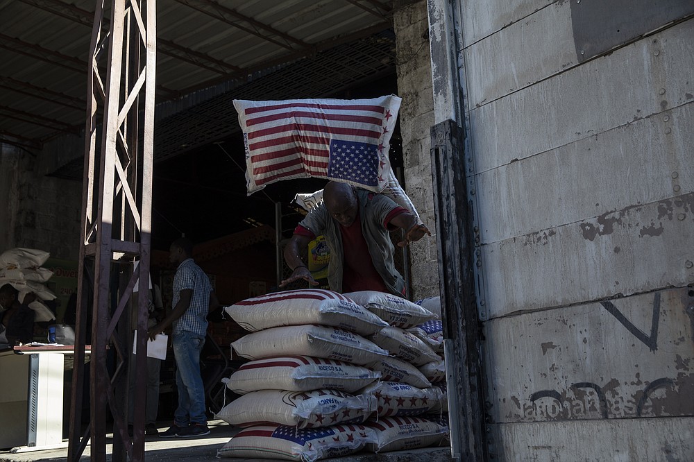 An employee carries a sack of rice imported from the United States inside a Shodecosa industrial park warehouse, in Port-au-Prince, Haiti, Wednesday, Sept. 29, 2021. Shodecosa is the country's largest industrial park, which warehouses 93 percent of the nation&#x2019;s imported food. (AP Photo/Rodrigo Abd)