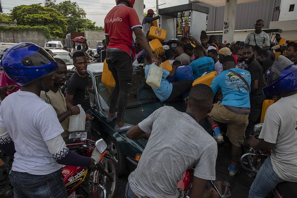People push and shove as they try to get their tanks filled at a gas station in Port-au-Prince, Haiti, Wednesday, Sept. 22, 2021. In addition to kidnappings, gangs are blamed for blocking gas distribution terminals and hijacking supply trucks, which officials say has led to a shortage of fuel. (AP Photo/Rodrigo Abd)