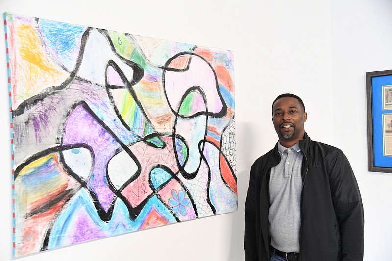 Anthony Tidwell, founder of C4K, stands next to a painting by Carrie Gaston and several C4K students. It will be for sale at The Birth of an Artist. - Photo by Tanner Newton of The Sentinel-Record