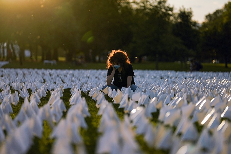 FILE - In this Sept. 17, 2021, file photo, Zoe Nassimoff, of Argentina, looks at white flags that are part of artist Suzanne Brennan Firstenberg's temporary art installation, &quot;In America: Remember,&quot; in remembrance of Americans who have died of COVID-19, on the National Mall in Washington. Nassimoff's grandparent who lived in Florida died from COVID-19. (AP Photo/Brynn Anderson, File)