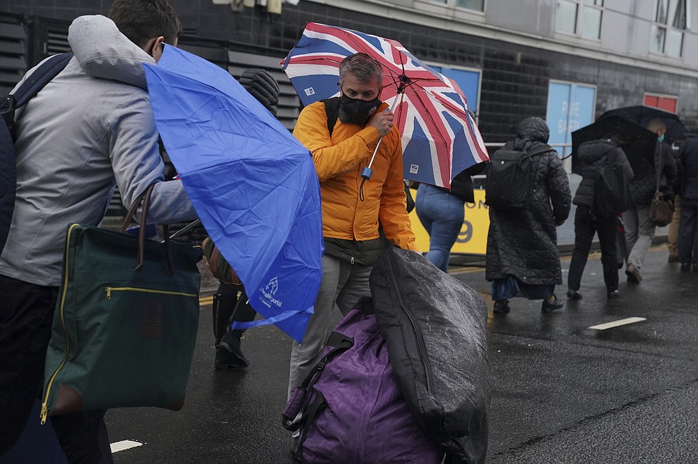 Delegates try to cope with the wet weather conditions as the wait to enter the Scottish Event Campus ahead of the COP26 Summit in Glasgow, Scotland, Sunday October 31, 2021. (Owen Humphreys/PA via AP)