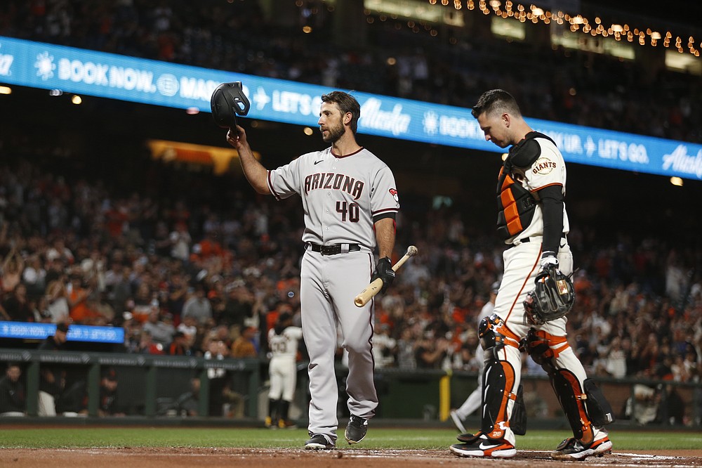 Arizona Diamondbacks' Madison Bumgarner, left, acknowledges the crowd before batting in front of San Francisco Giants' Buster Posey during the first inning of a baseball game in San Francisco, Thursday, Sept. 30, 2021. (AP Photo/Jed Jacobsohn)