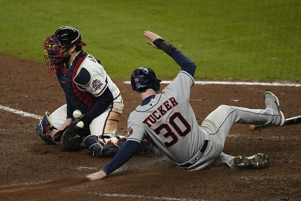 Houston Astros' Kyle Tucker scores past Atlanta Braves catcher Travis d'Arnaud on a single by Martin Maldonado during the seventh inning in Game 5 of baseball's World Series between the Houston Astros and the Atlanta Braves Sunday, Oct. 31, 2021, in Atlanta. (AP Photo/Ashley Landis)