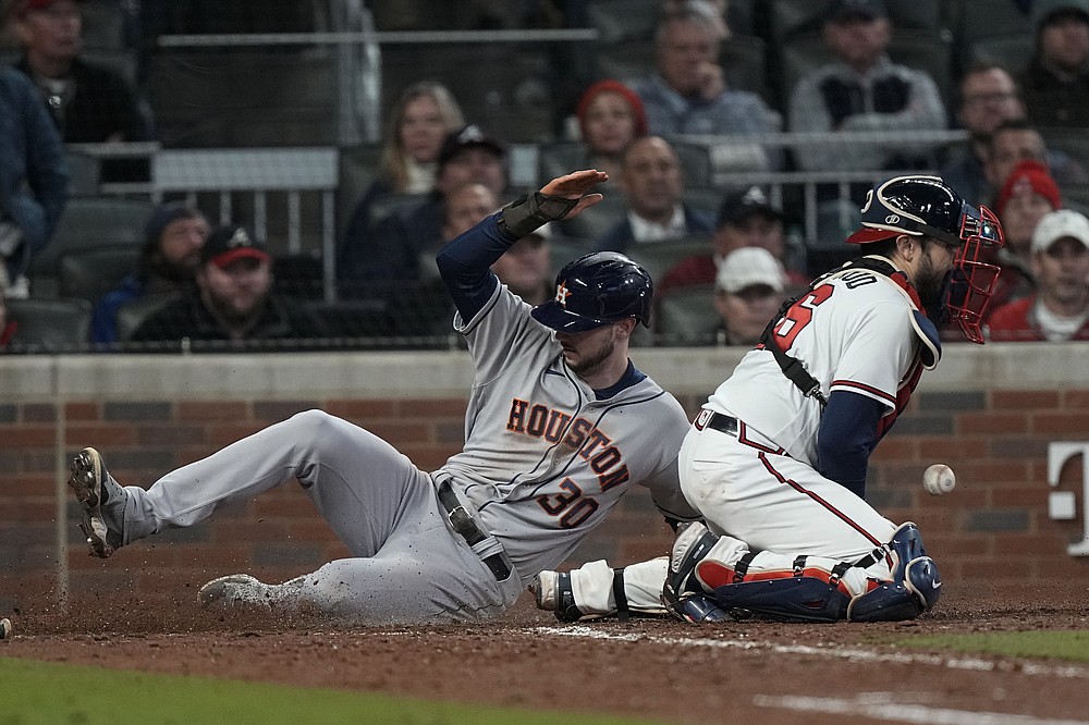 Houston Astros' Kyle Tucker scores past Atlanta Braves catcher Travis d'Arnaud on a single by Martin Maldonado during the seventh inning in Game 5 of baseball's World Series between the Houston Astros and the Atlanta Braves Sunday, Oct. 31, 2021, in Atlanta. (AP Photo/Brynn Anderson)