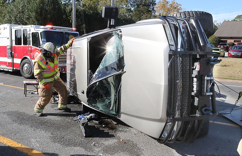 A Hot Springs firefighter works outside an overturned 2007 Chevrolet Silverado, one of three vehicles involved in an injury wreck in the 2800 block of Albert Pike Road that occurred shortly before 10 a.m. Monday. - Photo by Richard Rasmussen of The Sentinel-Record