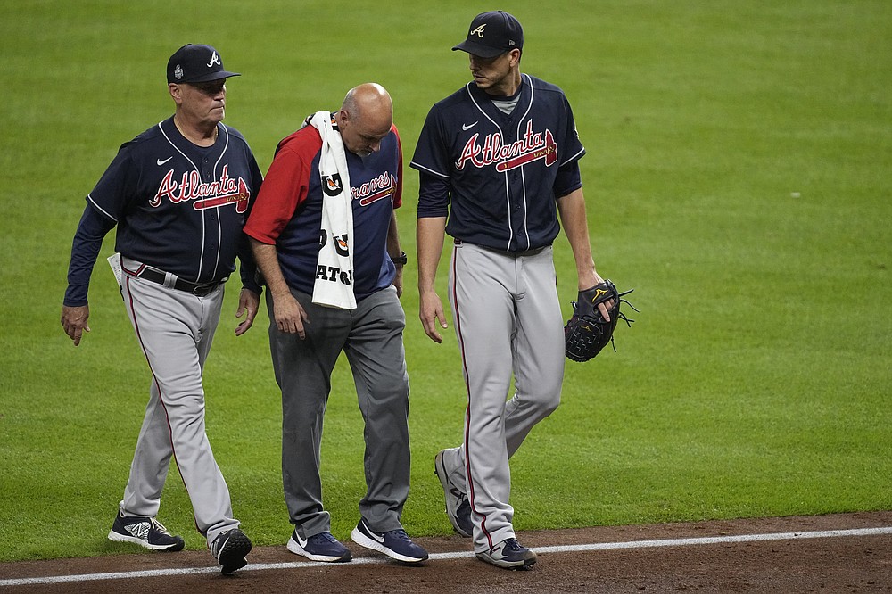 ADDS NAME OF BRAVES TRAINER AT CENTER AND BRAVES MANAGER AT LEFT- Atlanta Braves starting pitcher Charlie Morton, right, is helped off the field by Braves head athletic trainer George Poulis, center, during the third inning of Game 1 in baseball's World Series between the Houston Astros and the Atlanta Braves Tuesday, Oct. 26, 2021, in Houston. At left is Braves manager Brian Snitker. AP Photo/Eric Gay)
